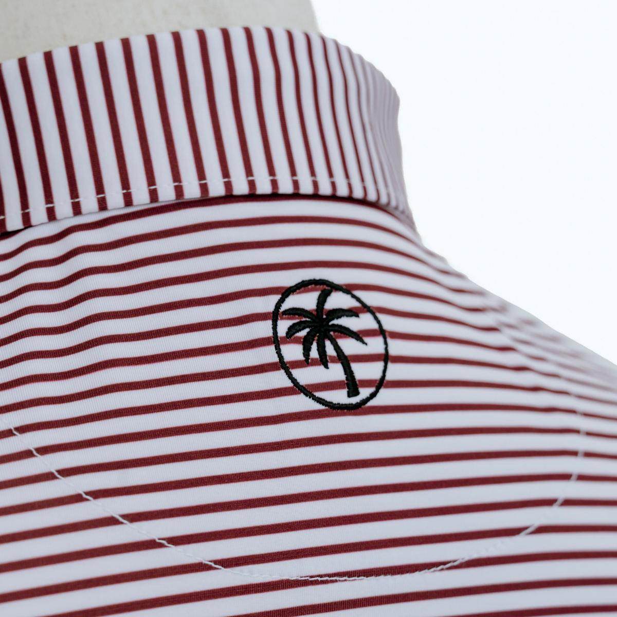 Close-up product detail of the Palmetto Clothing The Classic Stripe Polo in Garnet highlighting the premium fabric, refined craftsmanship, and elevated finish found in the best golf apparel.