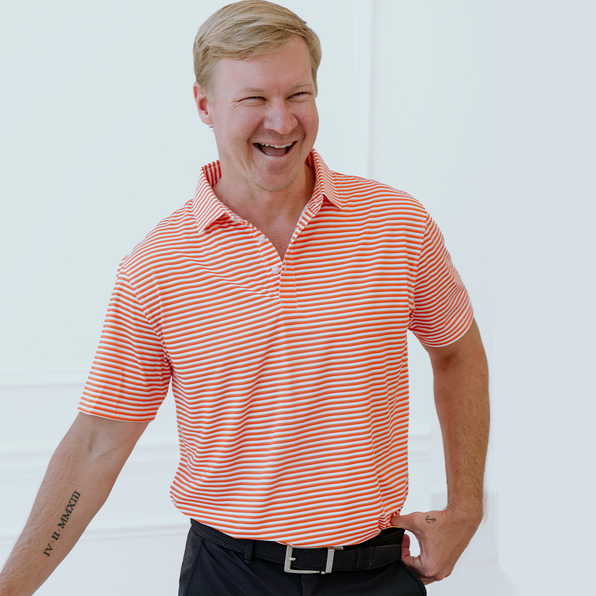 Model wearing the Palmetto Clothing The Double Double Polo in Orange featuring our signature double stripe design. A premium striped golf polo built with lightweight performance fabric and exceptional comfort for golfers.