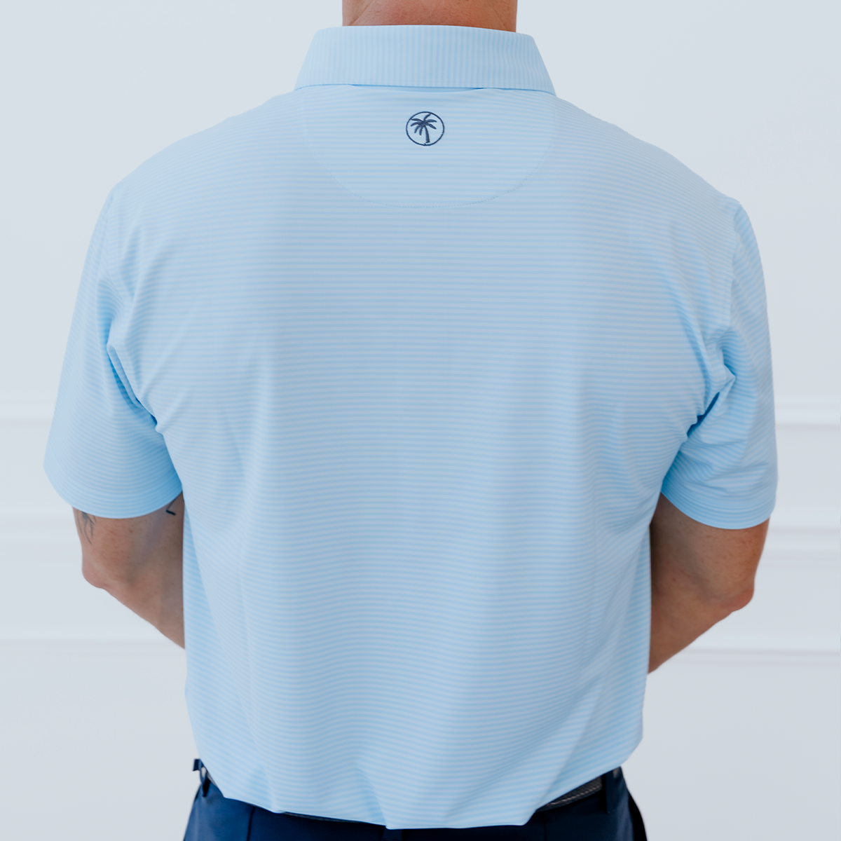 Back view of the Palmetto Clothing The Classic Stripe Polo in Sky Blue highlighting the athletic fit, breathable construction, and premium performance fabric built for every round.