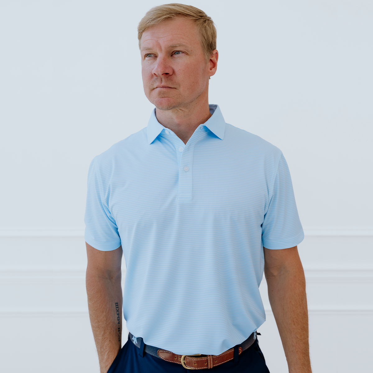 Model wearing the Palmetto Clothing The Classic Stripe Polo in Sky Blue, a timeless stripe golf polo crafted with lightweight performance fabric, exceptional comfort, and premium style for golfers on and off the course.