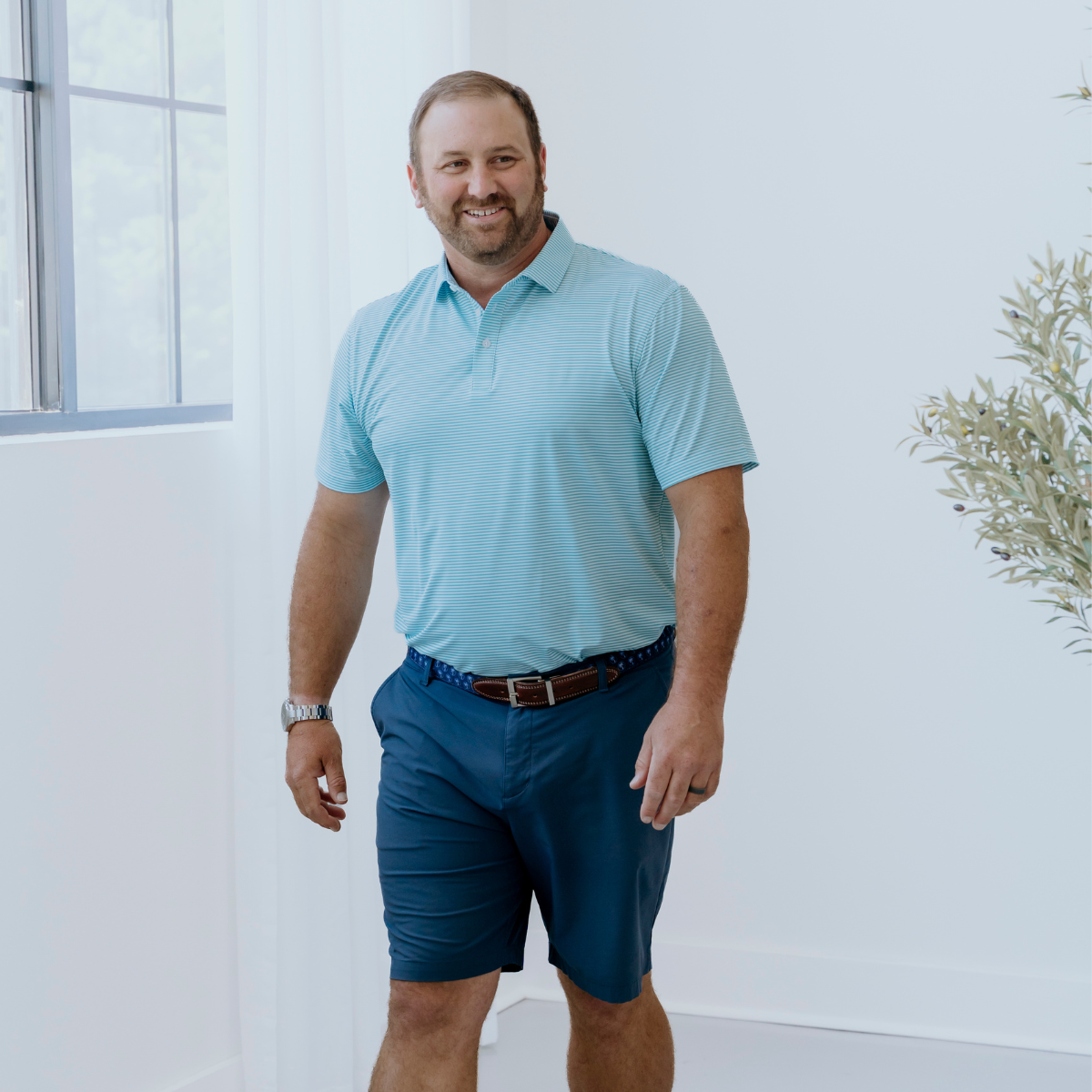 Model wearing the Palmetto Clothing The Classic Stripe Polo in Teal, one of our premium mens golf polo shirts crafted with lightweight, breathable performance fabric and exceptional everyday comfort.
