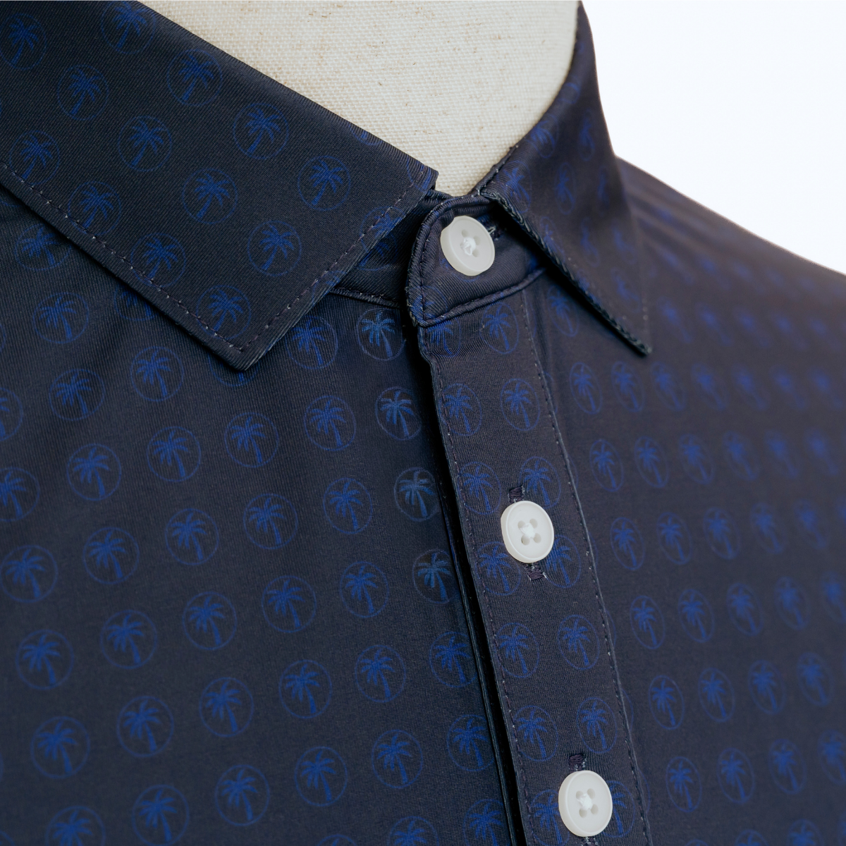 Close-up product detail of the Palmetto Clothing The Icon Polo in Navy and Blue showcasing the premium fabric, repeating logo design, refined stitching, and craftsmanship that make it one of our best golf polos.