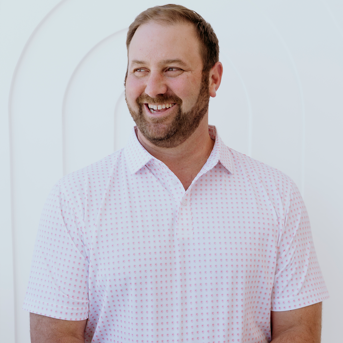 Front view of the Palmetto Clothing The Icon Polo in White and Peach displaying the repeating Palmetto logo design. One of our premium golf shirts for men combining timeless style with breathable performance fabric.