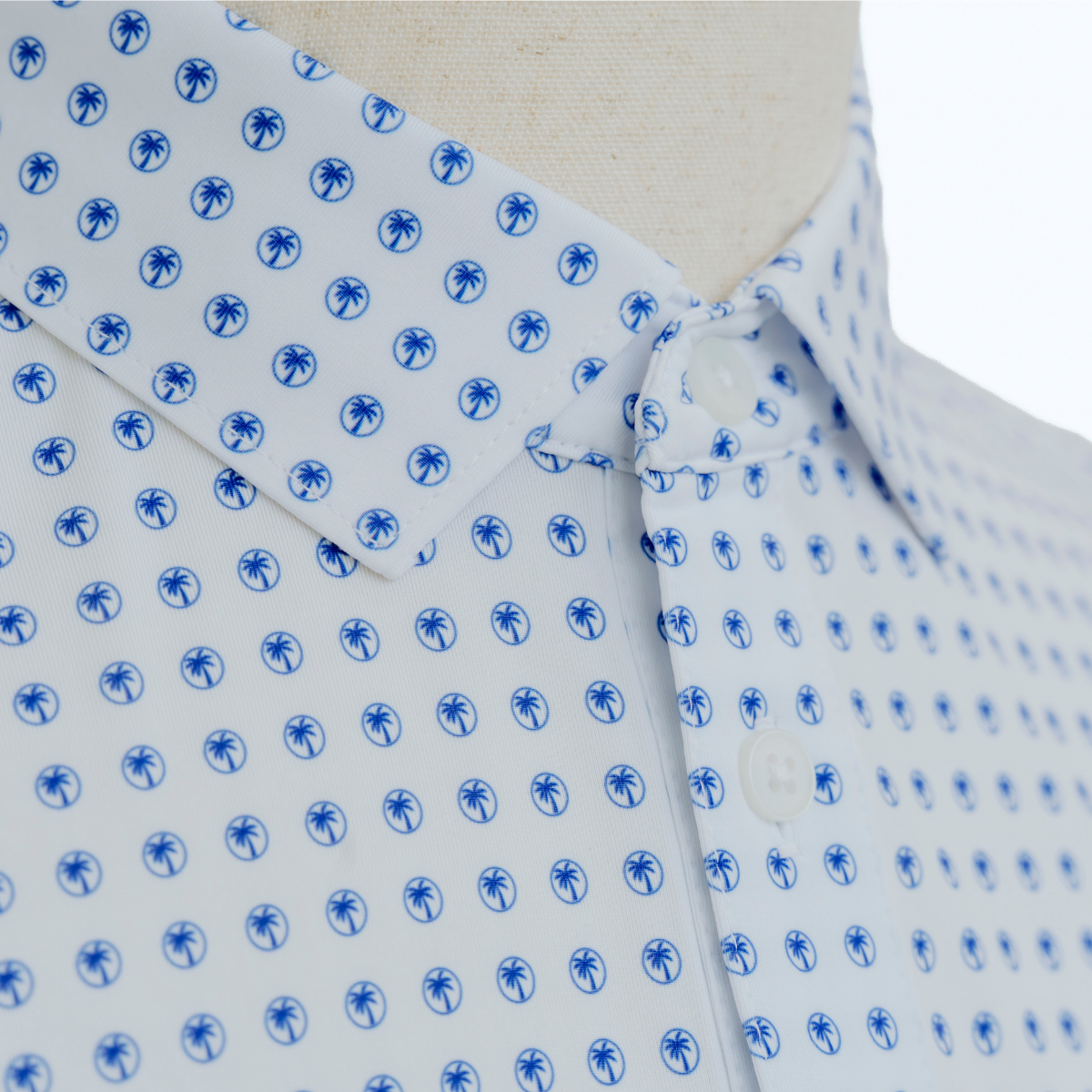 Close-up product detail of the Palmetto Clothing The Icon Polo in White and Bright Blue showcasing the premium fabric, repeating Palmetto logo pattern, refined stitching, and craftsmanship found in our men's golf polo shirts.