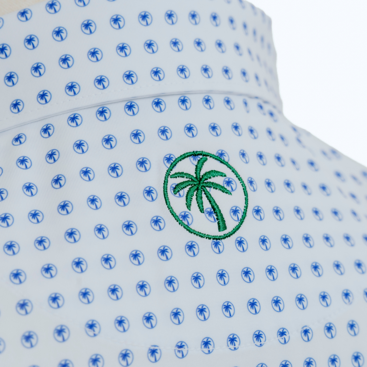 Close-up product detail of the Palmetto Clothing The Icon Polo in White and Bright Blue showcasing the premium fabric, repeating Palmetto logo pattern, refined stitching, and craftsmanship found in our men's golf polo shirts.