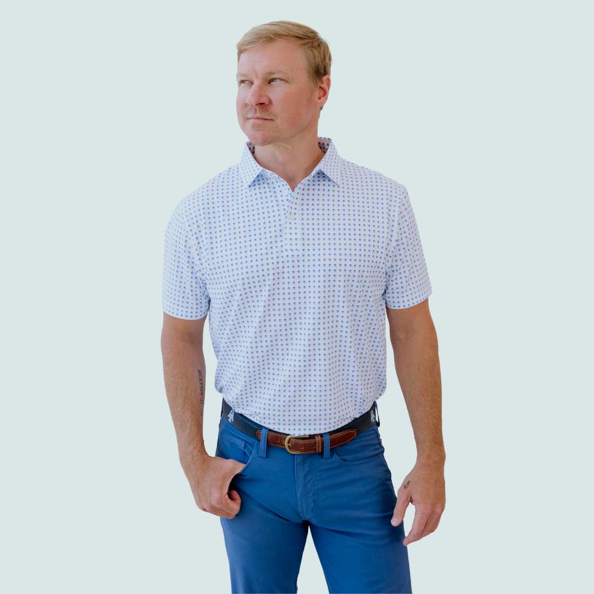 Model wearing the Palmetto Clothing The Icon Polo in White and Bright Blue featuring our signature repeating logo pattern. One of our premium mens golf polo shirts, designed with lightweight performance fabric and exceptional comfort for every round.