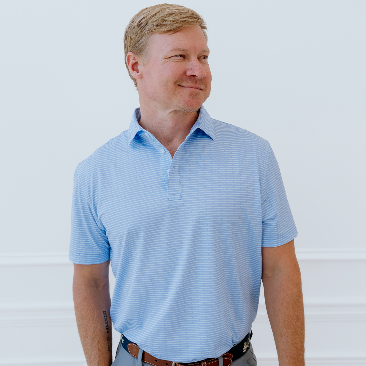 Model wearing the Palmetto Clothing The Pin Dash Polo in Medium Blue with Gray pin dash stripes, one of our premium mens golf polo shirts crafted with lightweight performance fabric, exceptional comfort, and timeless style for golfers on and off the course.