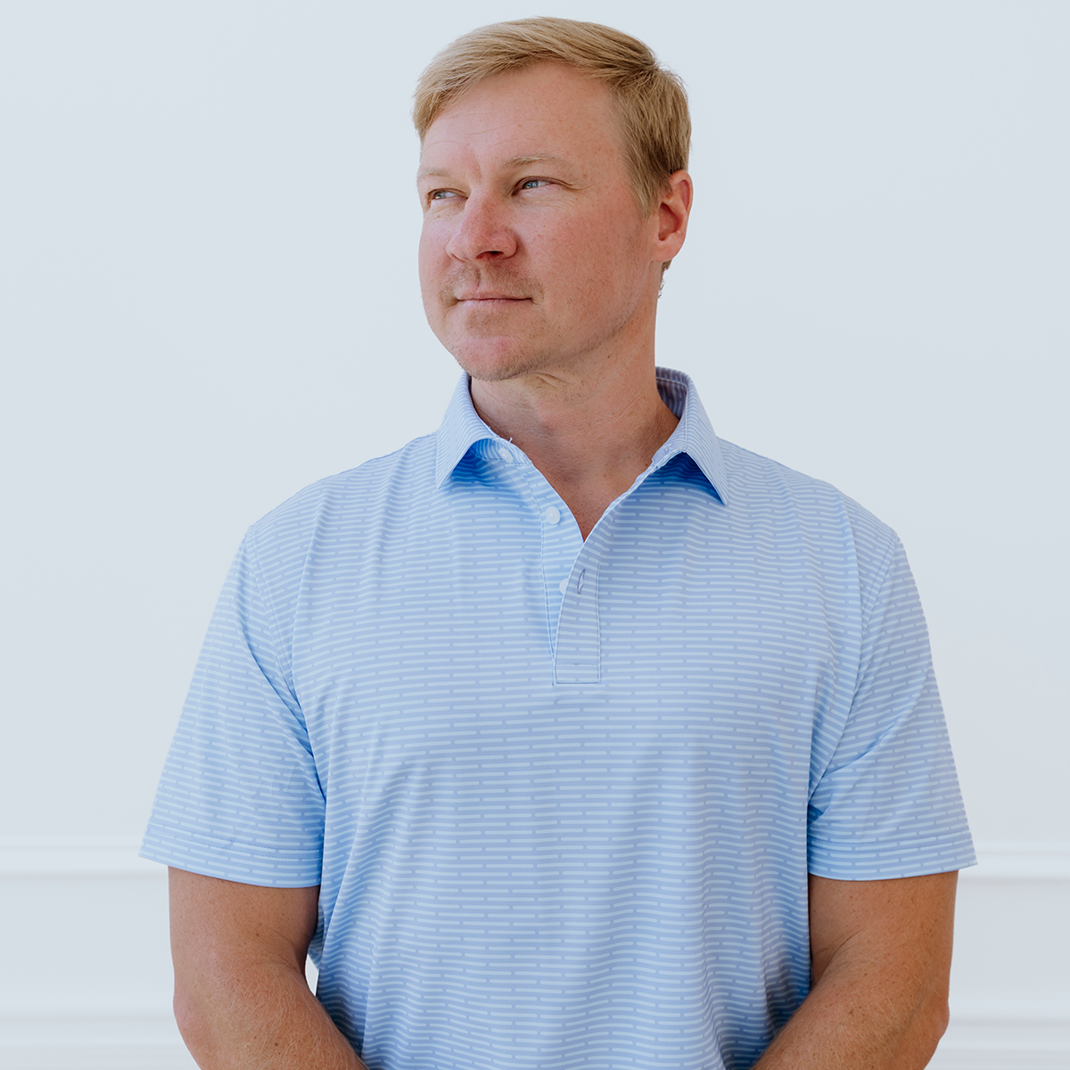 Front view of the Palmetto Clothing The Pin Dash Polo in Medium Blue featuring the signature gray pin dash stripe pattern. A premium high quality golf shirt designed with breathable performance fabric and modern style.
